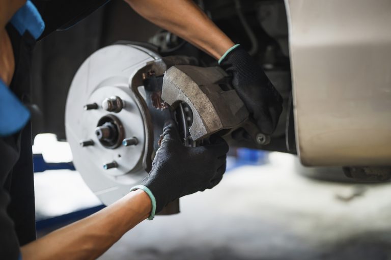 Mechanic installing a car brake caliper and pads