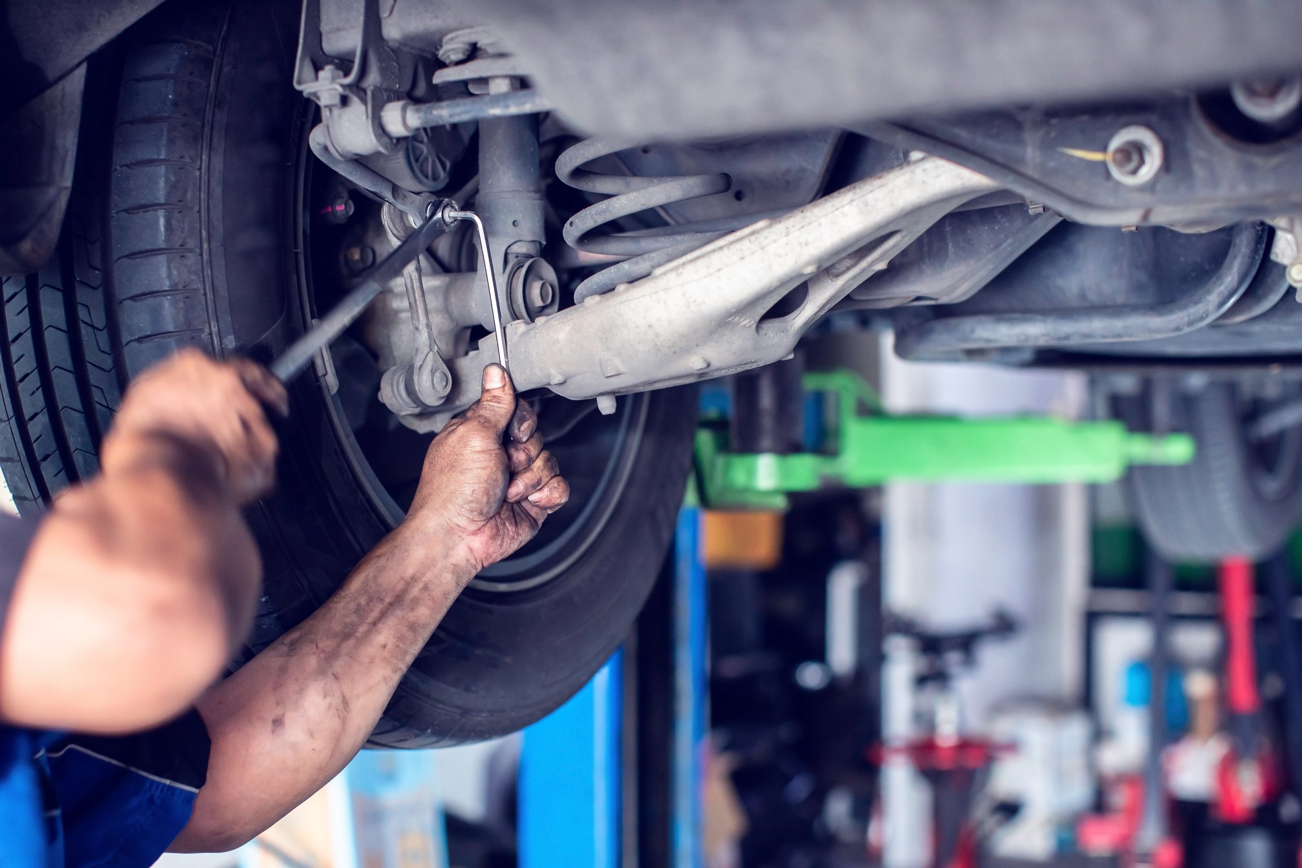 Mechanic working underneath a vehicle to repair suspension